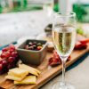 clear wine glass with brown liquid beside red and black berries on brown wooden table